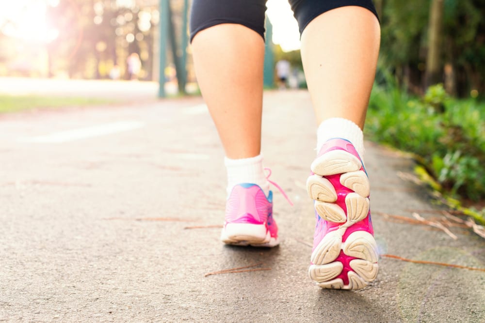 Closeup of a womans' legs walking away wearing sneakers to avoid foot pain while working out.